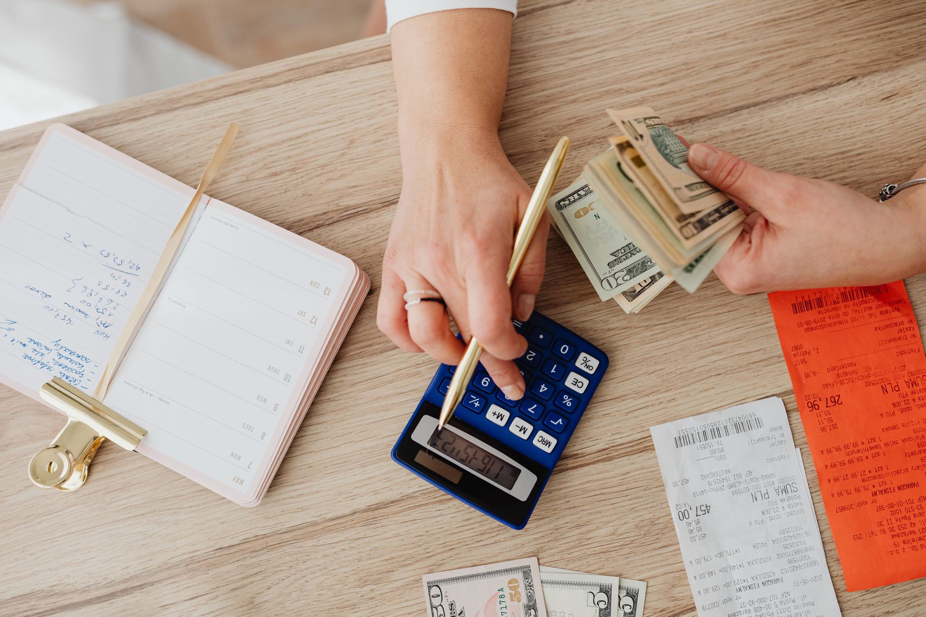 person holding paper bills while using a calculator