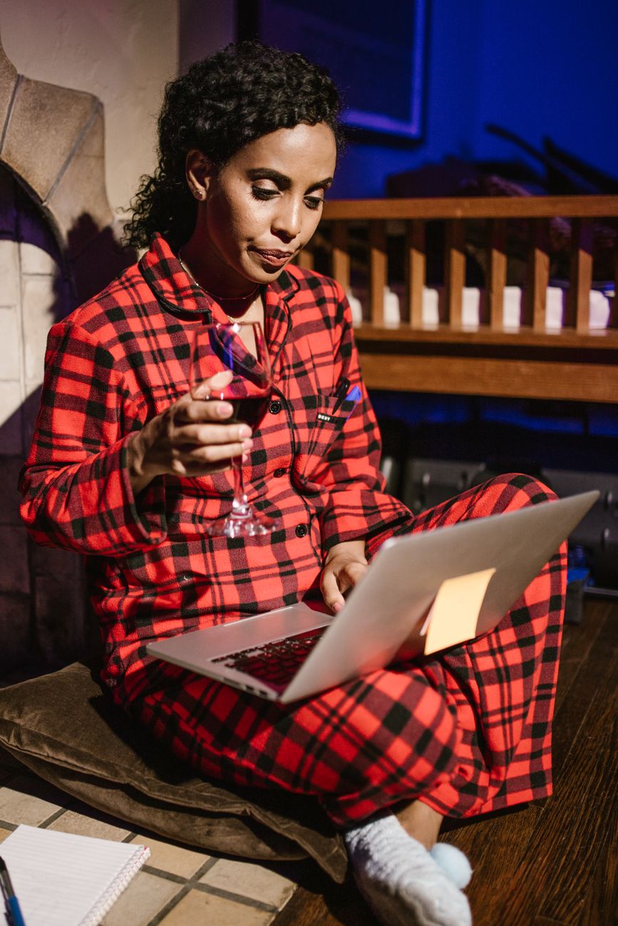 woman holding a glass of wine using laptop