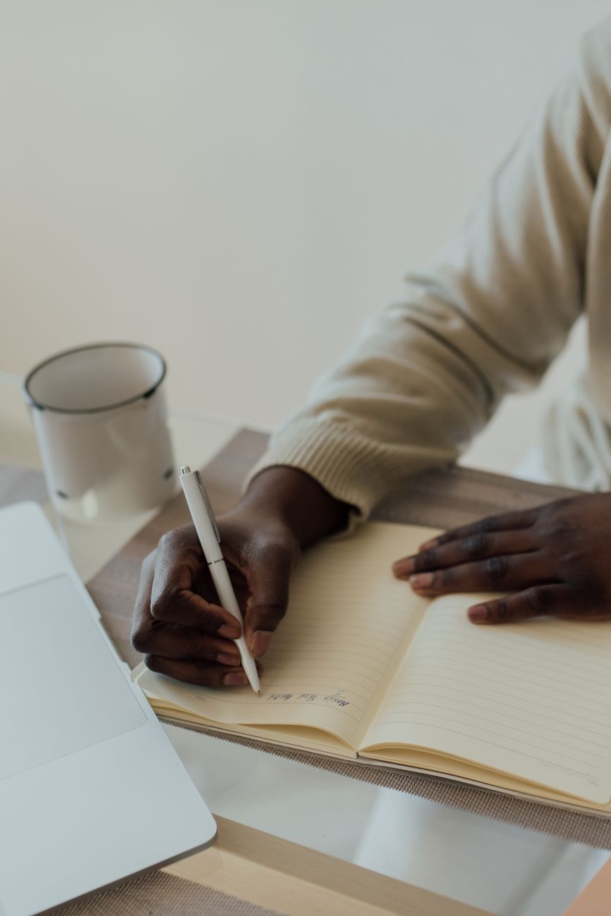 person with white ballpen writing on a notebook