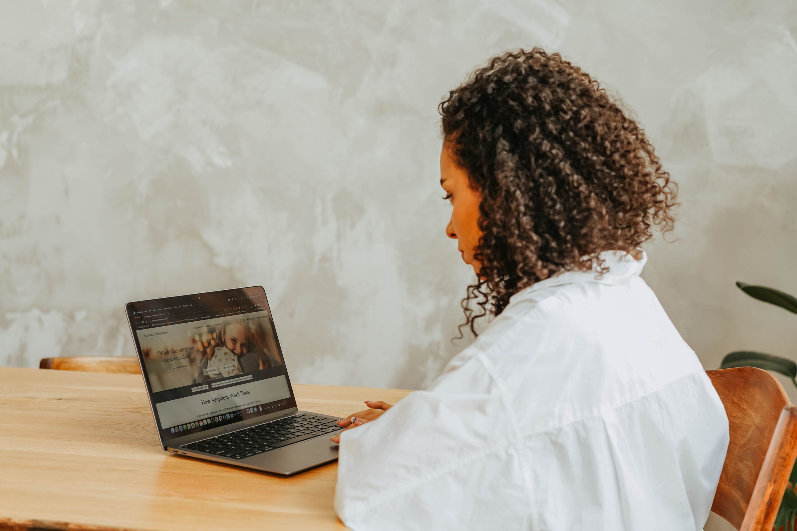 Person using a laptop at a light wooden table.
